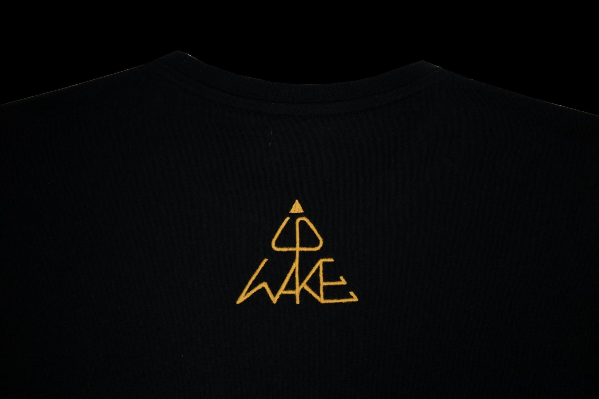 Pyramidenförmige WAKE UP Wortbildmarke – goldene Stickerei auf Oversized-Shirt Rückseite